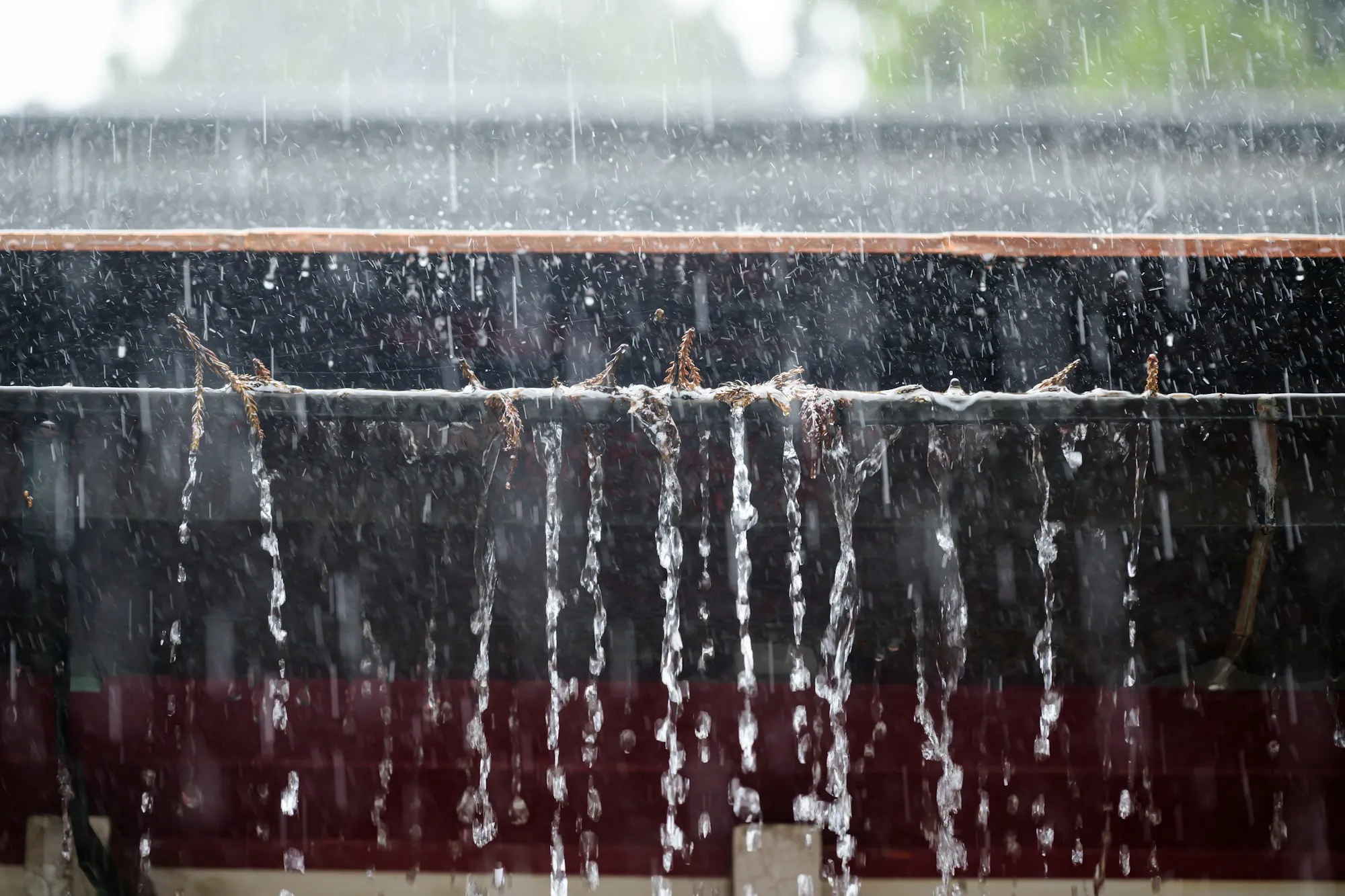 Rain streaming over the lip of an overflowing gutter