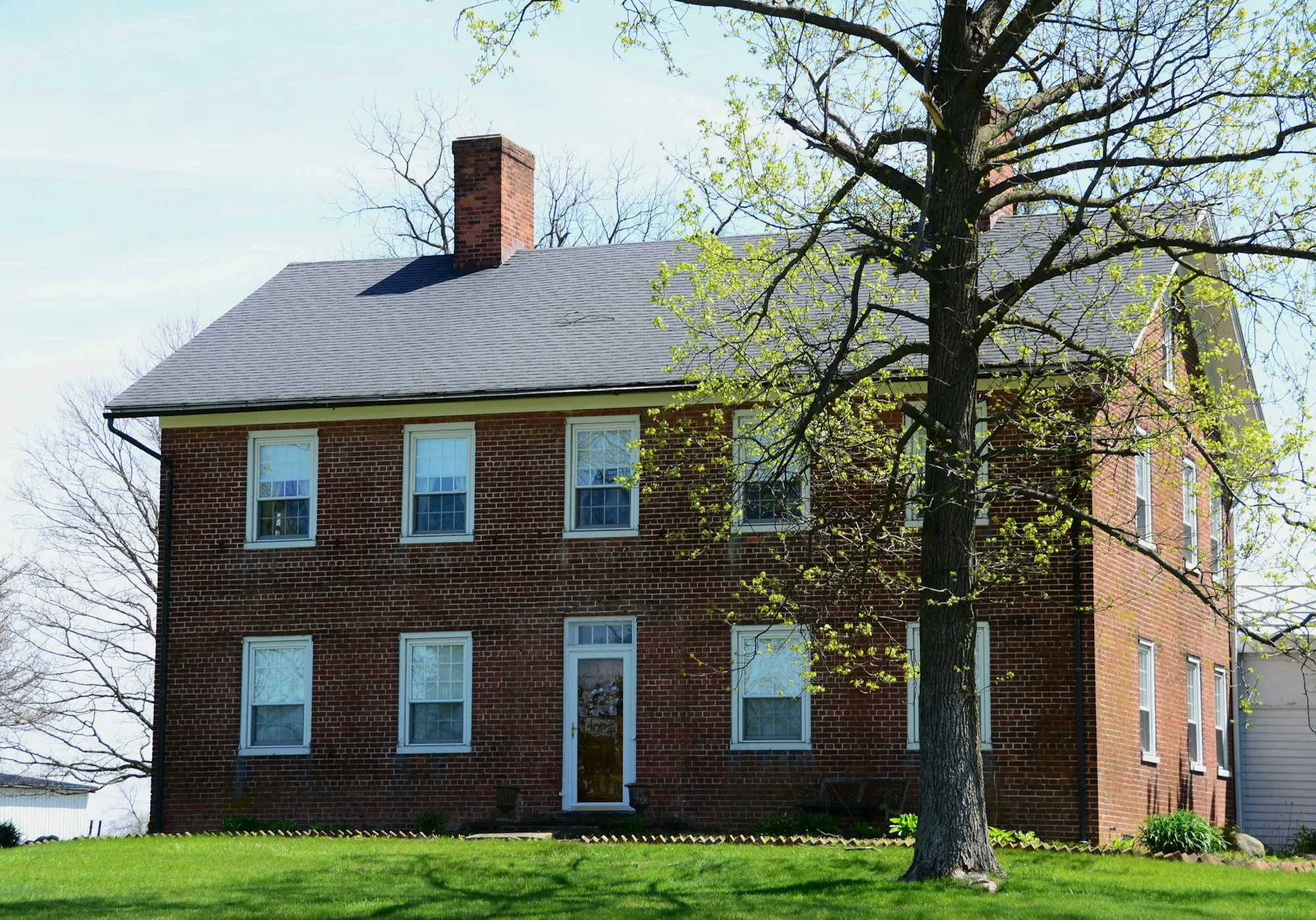 Brick colonial house with a chimney and spring trees